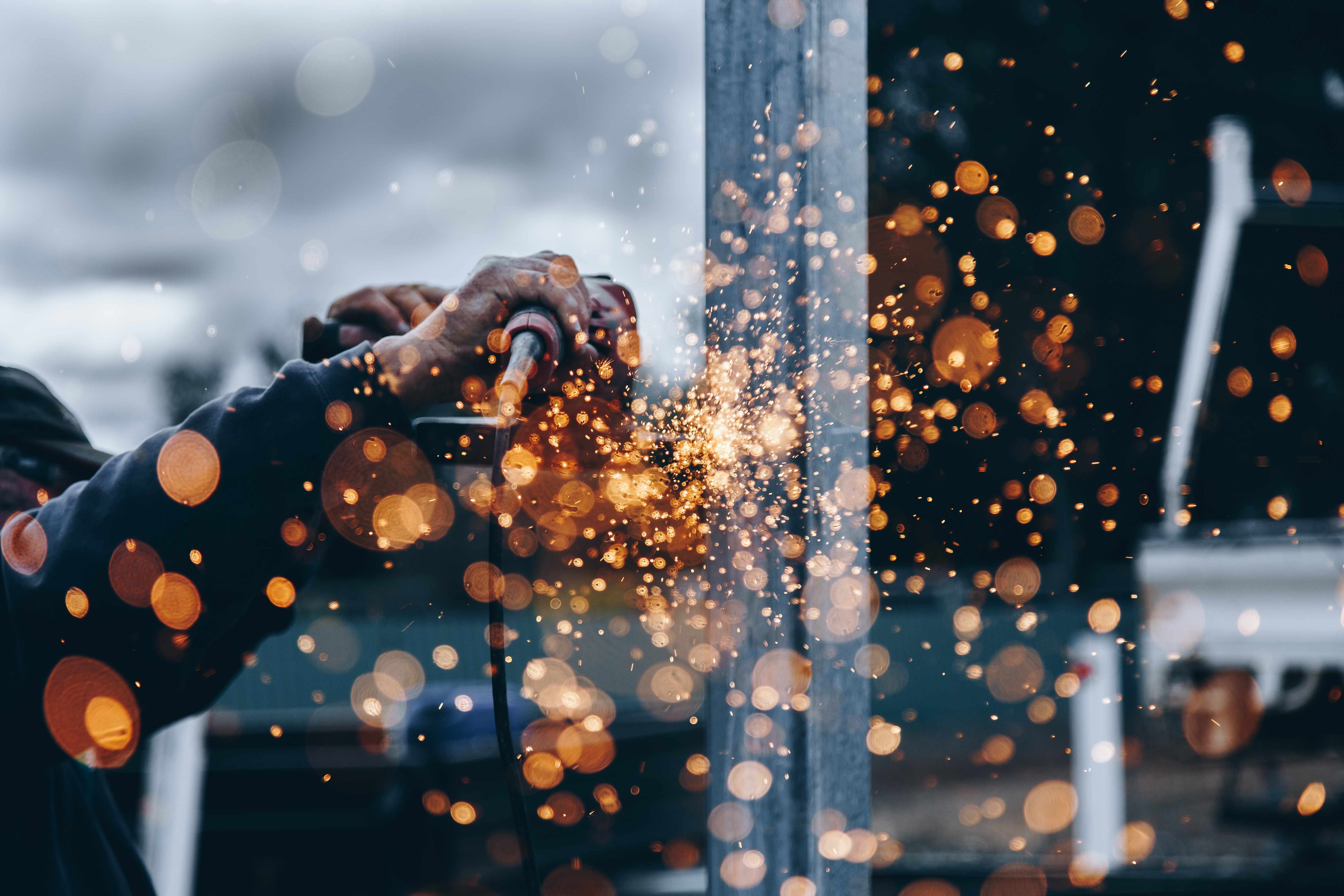 A builder cutting metal with an angle grinder, sparks flying